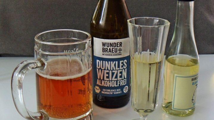 Ein Glas dunkles Weizenbier steht neben anderen alkoholfreien Getr&auml;nken auf einem Tisch, ideal f&uuml;r Genuss ohne Alkohol.
