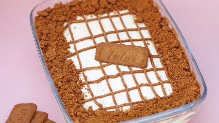 Ein k&ouml;stlicher Lotus Nachtisch in einer Glasform, garniert mit Keksbr&ouml;seln und einer schokoladigen Dekoration.