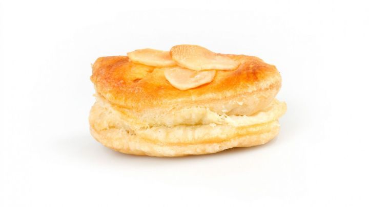 Zarte Puddingteilchen aus Bl&auml;tterteig liegen appetitlich auf einem wei&szlig;en Untergrund, verziert mit mandel&auml;hnlichen Scheiben.