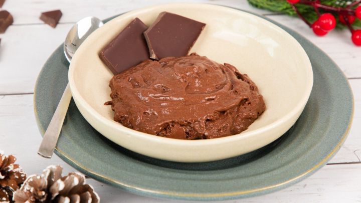 Eine cremige Schokocreme in einer Sch&uuml;ssel, umgeben von Schokoladentafeln und dekorativem, festlichem Umfeld.