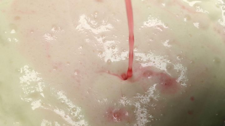 Bunte Sahne wird in eine helle, cremige Masse gegossen, die eine samtige Textur und lebendige Farben zeigt.