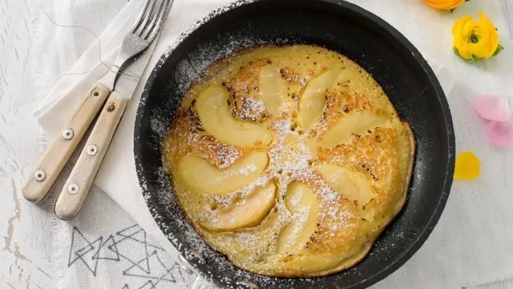 Hübsche Pfannkuchen-Variante mit Apfelspalten: Statt Apfelstücke schneidest du dünne Spalten und legst sie sonnenförmig in die Pfanne. Darüber wird der Teig gegossen.
