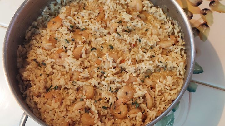 Eine gro&szlig;e Pfanne mit Cajun-Garnelen-Reis steht auf einem bunten Fliesenmuster, reichlich gef&uuml;llt und dampfend.