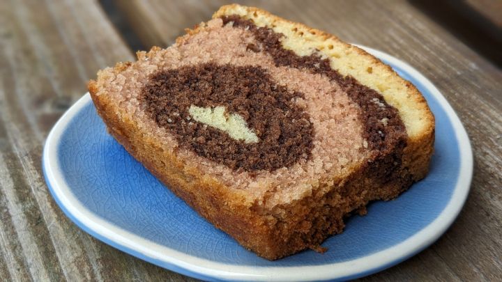 Saftiges St&uuml;ck F&uuml;rst-P&uuml;ckler-Kuchen liegt auf einem blauen Teller und pr&auml;sentiert die charakteristischen Schokoladen- und Vanilleschichten.