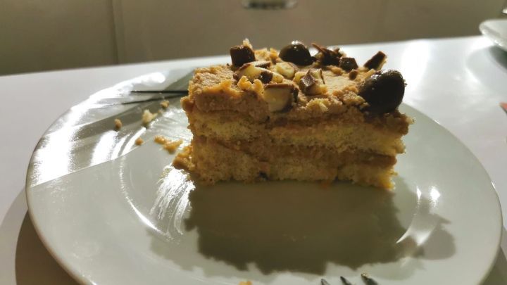 Eine schmackhafte Kinderschokoladen-Nachspeise liegt auf einem Teller und zeigt geschichteten Kuchen, garniert mit Schokoladensplittern.