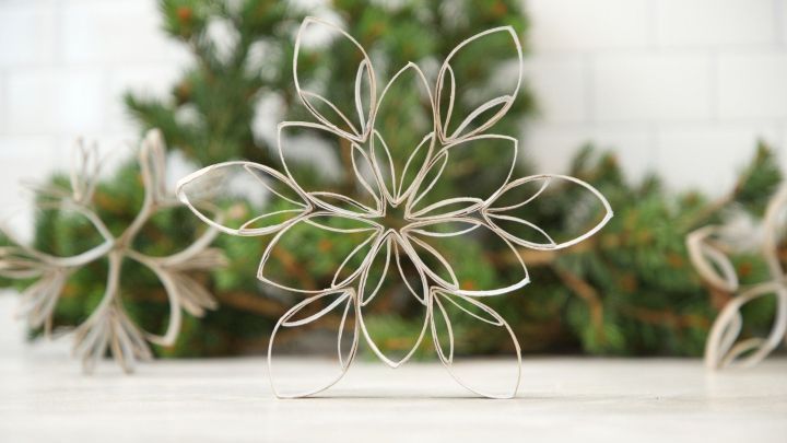 Eine Sternform aus Klopapierrollen steht auf einem Tisch, umgeben von gr&uuml;nen Zweigen, und strahlt Bastelideen aus.