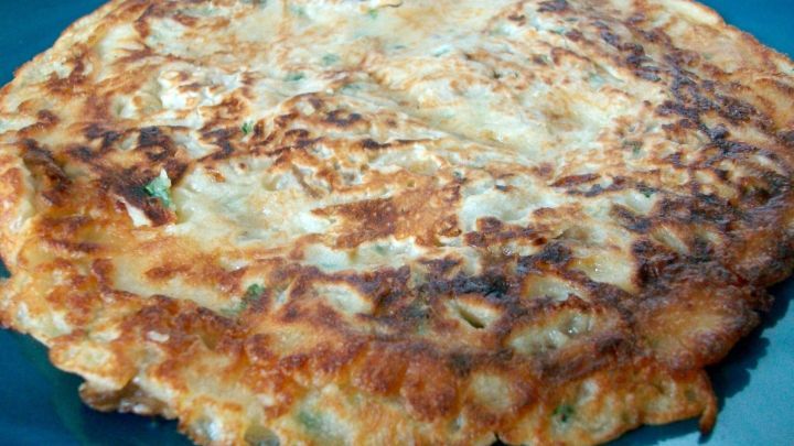 Ein goldbrauner Auberginen-Pfannkuchen liegt auf einem blauen Teller und wartet darauf, serviert zu werden.