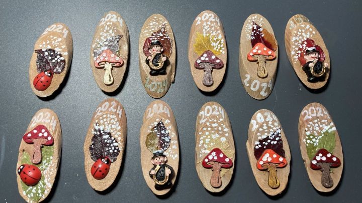 Bunte Gl&uuml;cksbringer aus Holz f&uuml;r den Jahreswechsel, verziert mit Pilzen, Marienk&auml;fern und Jahreszahlen 2024.