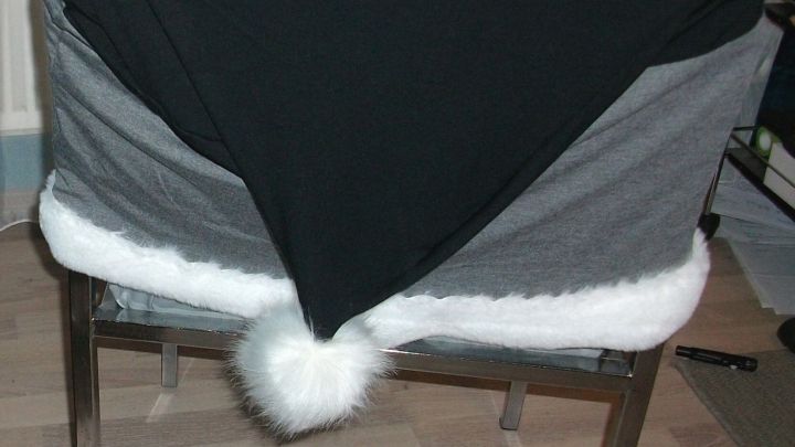 Eine Stuhlhusse in Form einer Nikolausm&uuml;tze &uuml;ber einem metallischen K&uuml;chenstuhl, passend f&uuml;r die Weihnachtszeit.