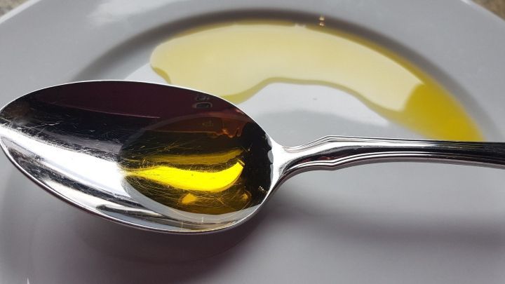 Ein L&ouml;ffel mit gl&auml;nzendem Lein&ouml;l liegt auf einem wei&szlig;en Teller, umgeben von einer hellen, neutralen Oberfl&auml;che.