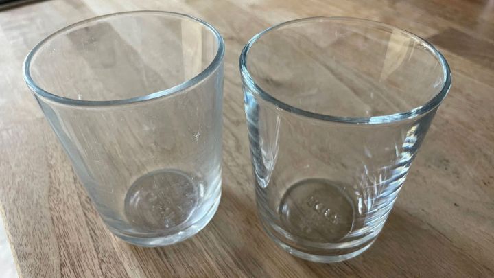 Zwei matte Gl&auml;ser stehen auf einem Holzuntergrund, bereit, im Geschirrsp&uuml;ler gl&auml;nzend gereinigt zu werden.