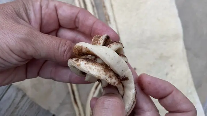 Teigstreifen etwas versetzt von oben nach unten &uuml;ber Daumen und Zeigefinger legen.