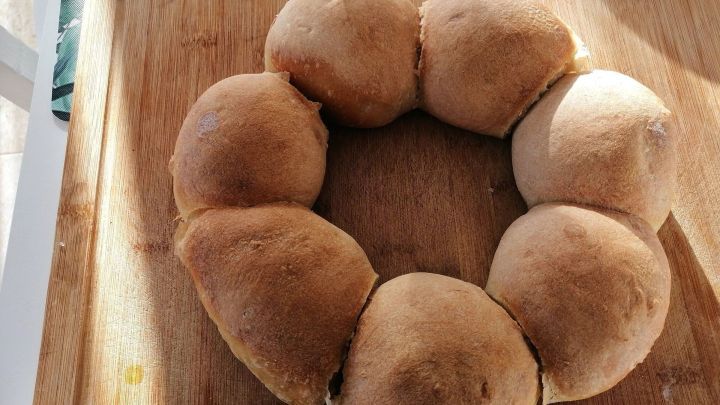 Runde frische Sonntagsbr&ouml;tchen liegen auf einem Holzbrett und warten auf das Essen in einer warmen, hellen Umgebung.