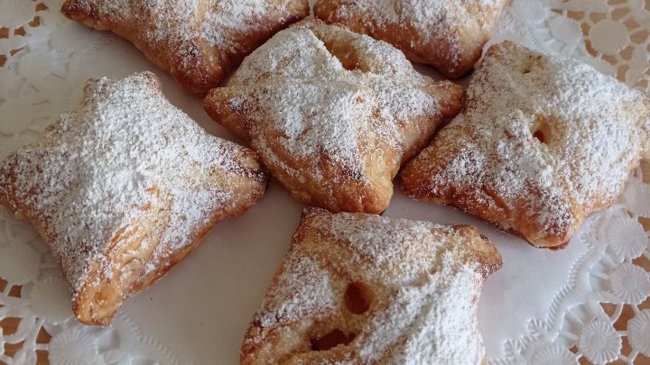 Bl&auml;tterteig-H&auml;ppchen sind auf einem Spitzendeckchen arrangiert und leicht mit Puderzucker best&auml;ubt.