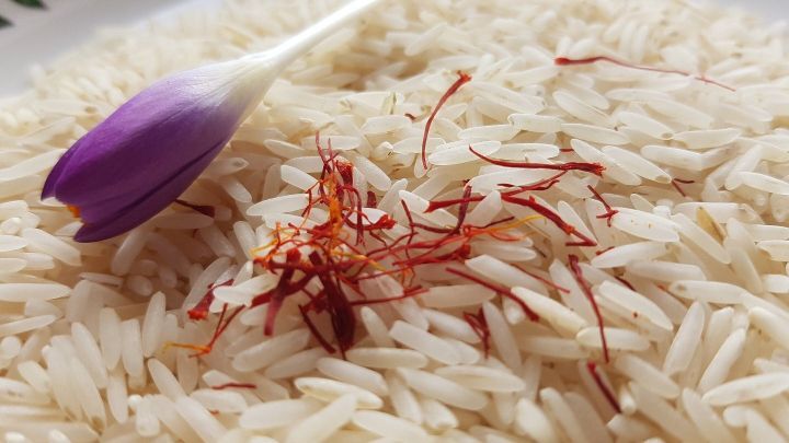 Wei&szlig;er Reis wird mit roten Safranf&auml;den und einer lila Krokusbl&uuml;te dekoriert, was eine exquisite Kombination zeigt.