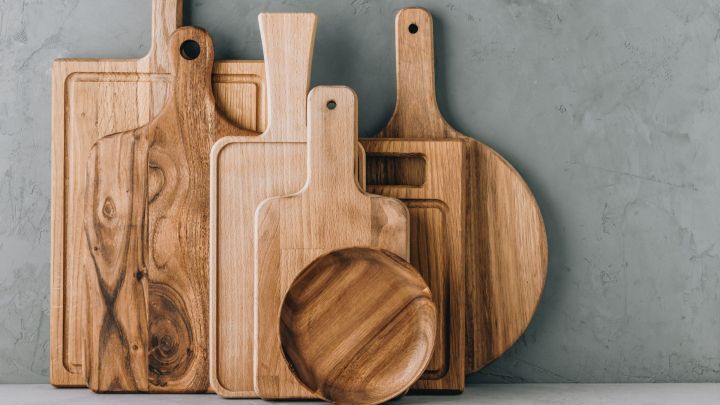 Mehrere Holzbrettchen stehen auf einem hellen Tisch vor einer grauen Wand und warten darauf, richtig gereinigt und gepflegt zu werden.