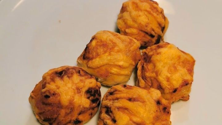 Kleine, goldbraune Pizzabr&ouml;tchen liegen auf einem wei&szlig;en Teller, bereit als k&ouml;stlicher Partysnack serviert zu werden.