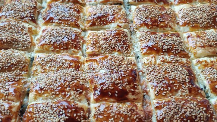 K&auml;se-Schinken-Bl&auml;tterteig-Snacks sind goldbraun gebacken, quadratisch geschnitten und mit Sesam bestreut.