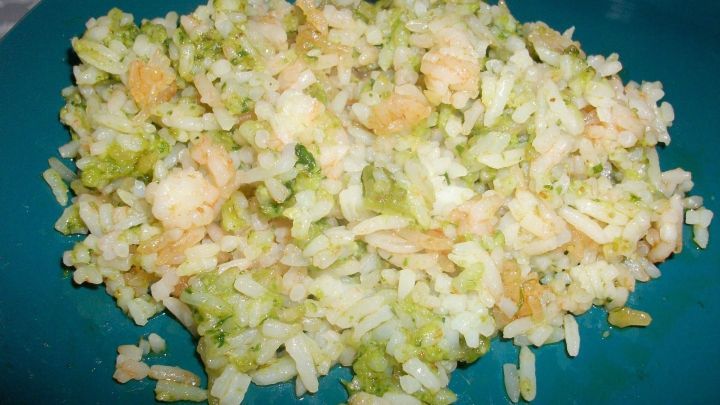 Ein Teller mit Reis, vermischt mit Walnuss-B&auml;rlauch-Pesto und Garnelen, umgeben von einem blauen Hintergrund.