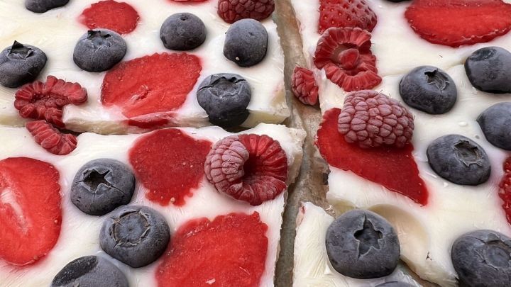 Kalter Joghurt-Snack mit frischen Beeren ist auf Backpapier verteilt und in St&uuml;cke geschnitten, ideal f&uuml;r hei&szlig;e Tage.