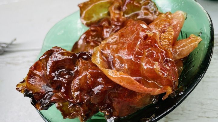 Kandierter Speck liegt gl&auml;nzend in einer gr&uuml;nen Schale, umgeben von einer hellen Holzoberfl&auml;che.