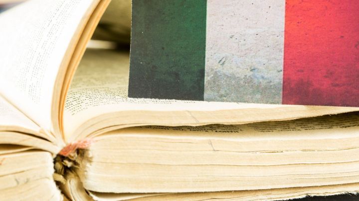 Ein aufgeschlagenes Buch liegt offen, w&auml;hrend eine italienische Flagge darauf sichtbar ist. Typische italienische Begriffe werden vermittelt.