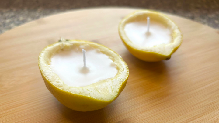 Zwei halbierte Zitronen wirken als Kerzen auf einem Holzbrett, bereit zur Verwendung gegen M&uuml;cken.