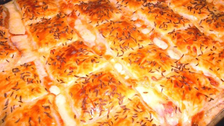 Zuf&auml;llig angeordnete, goldbraune Bl&auml;tterteigst&uuml;cke mit w&uuml;rziger F&uuml;llung aus Salami und Frischk&auml;se, gebacken.