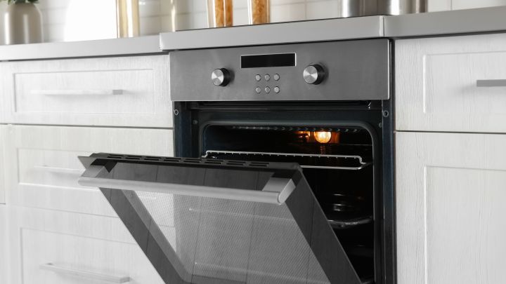 Ein offener, moderner Backofen in einer K&uuml;che strahlt Sauberkeit aus; die Lampe im Inneren leuchtet.