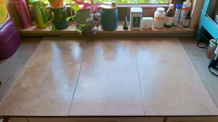 Fliesen bedecken Arbeitsplatte in K&uuml;che; Pflanzen und Dosen auf Fensterbank daneben; Datum unten rechts: 25. Aug. 2024.