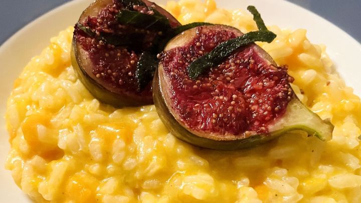 Risotto mit Butternut-K&uuml;rbis, garniert mit frischen Feigen und frittiertem Salbei, serviert auf einem wei&szlig;en Teller.