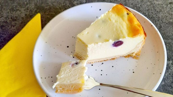 Ein St&uuml;ck herbstlicher K&auml;sekuchen mit Weintrauben liegt auf einem wei&szlig;en Teller, begleitet von einer gelben Serviette.