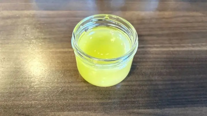 Ein Glas mit selbstgemachter Handcreme steht auf einem h&ouml;lzernen Tisch.