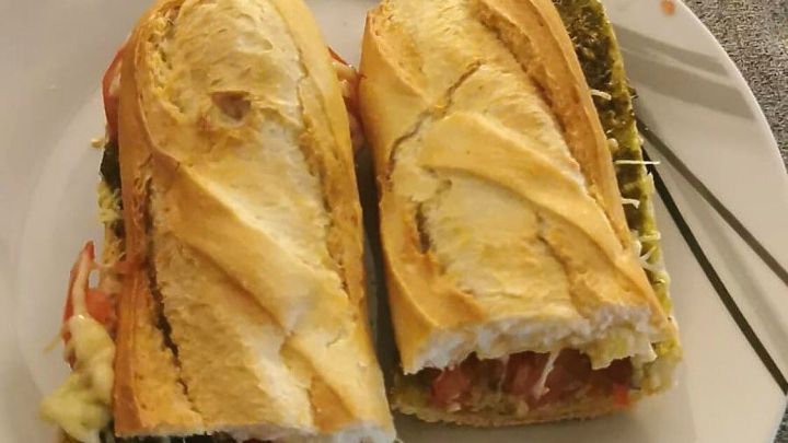 Zwei knusprige Baguette-Sandwiches auf einem Teller, gef&uuml;llt mit frischen Zutaten, liegen auf einem grauen Tisch.