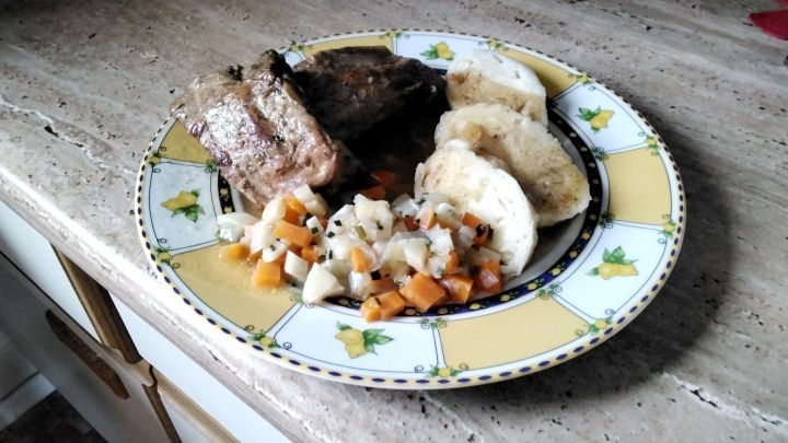 Ein Teller mit Petersilienwurzel-Karotten-Gem&uuml;se als Beilage zu Fleisch und Kn&ouml;deln serviert.