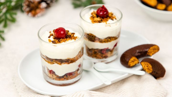 Zwei Gl&auml;ser Lebkuchen-Tiramisu mit Schichten aus Creme und Lebkuchen, dekoriert mit Kirschen, auf einem Teller mit L&ouml;ffeln.