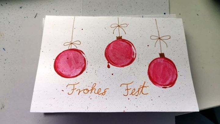 Gestalte Weihnachtskarten selbst. Diese handgemalte Karte mit roten Kugeln und der Aufschrift "Frohes Fest" inspiriert kreative Ideen f&uuml;r die festliche Jahreszeit.