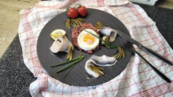 Labskaus: Ein norddeutscher Klassiker mit Corned Beef, Kartoffel und Rote Bete. Mit Matjes, Hering, Gew&uuml;rzgurken und Spiegelei kunstvoll angerichtet auf Schiefer. Probiere dieses traditionelle Gericht und genie&szlig;e den besonderen Geschmack.