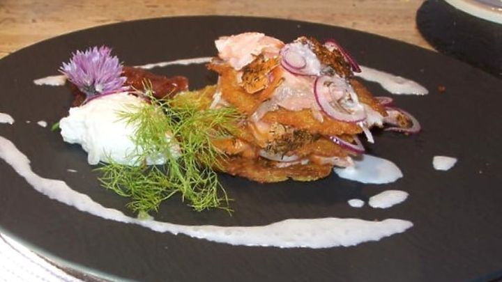 Kartoffelpuffer trifft auf ger&auml;ucherten Lachs und Meerrettichschaum: Ein herzhaftes Gericht, das elegante Aromen vereint. Dieses Bild zeigt die kunstvolle Anrichtung und verlockende Texturen, die im Artikel beschrieben werden.