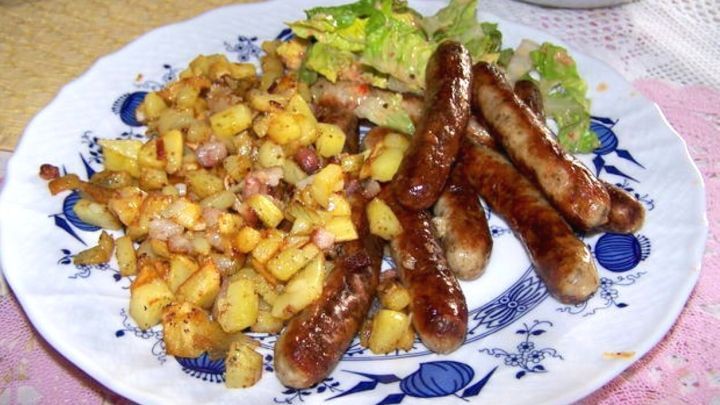 Knusprige Bratkartoffeln mit Speck und goldbraun gebratenen N&uuml;rnberger Bratw&uuml;rsten bilden ein herzhaftes Gericht, das einfach zubereitet werden kann. Dazu ein frischer Salat.
