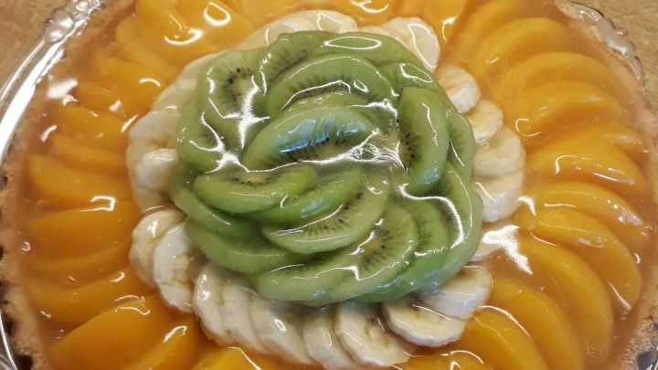 Obsttorte mit Pfirsichen, Kiwis und Bananen mit klarer Glasur &uuml;bergossen.