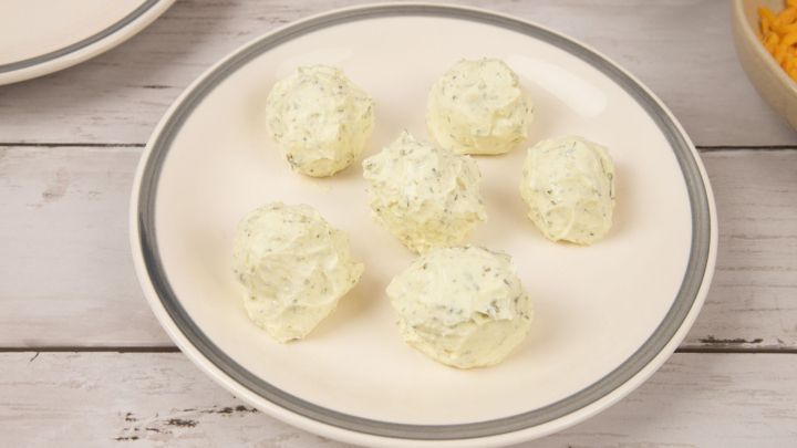 Rolle den Frischk&auml;se vorsichtig zu kleinen Kugeln. Etwas einfacher geht es, wenn du ihn vorher mit geriebenen Mandeln vermengst.