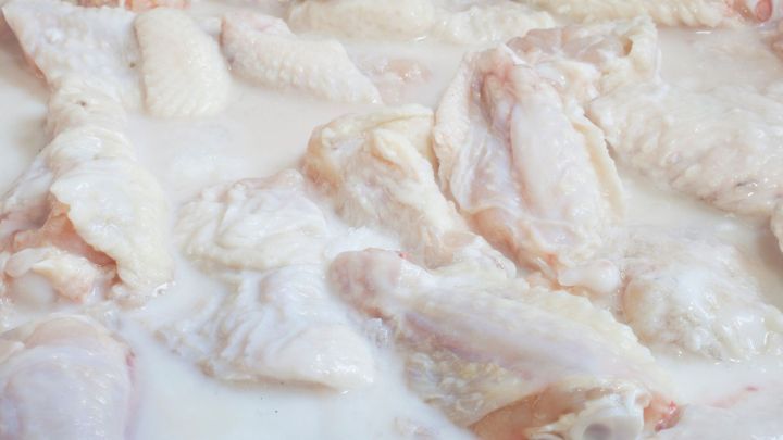 Putenfleisch liegt in einer milchigen Marinade, w&auml;hrend es zur Zubereitung in einer gro&szlig;en Sch&uuml;ssel vorbereitet wird.