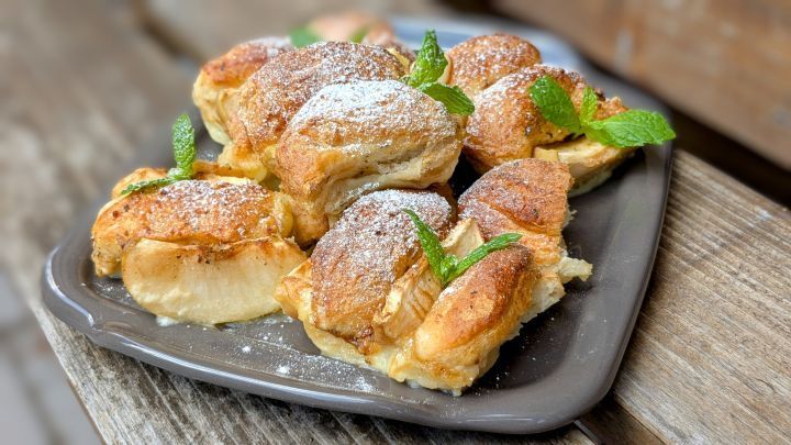 Milchbr&ouml;tchen-Auflauf mit Pudding und Apfel: Saftig, goldbraun gebacken und mit frischer Minze und Puderzucker garniert.