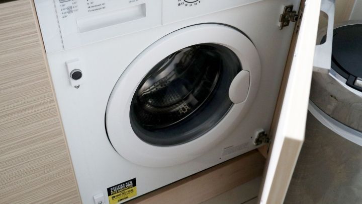 Eine Waschmaschine steht ge&ouml;ffnet in einer modernen K&uuml;che, bereit f&uuml;r den Umzug, um W&auml;sche zu reinigen.