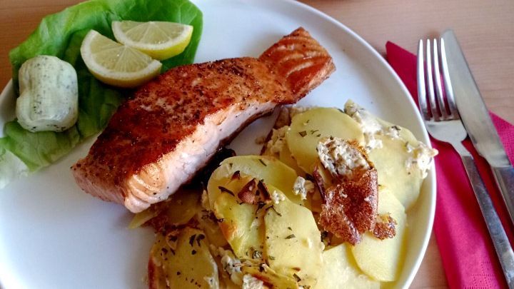 Gebratenes Lachsfilet mit Kartoffelgratin, garniert mit einem Salatblatt und Zitronenviertel, dazu Kr&auml;uterbutter und ein kleiner Salat,  
