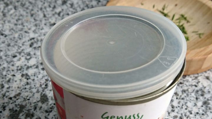 Konservendose, Inhalt teilweise entnommen, mit aufgelegtem transparenten Deckel als Ersatz f&uuml;r den Blechdeckel zum wieder Verschlie&szlig;en.