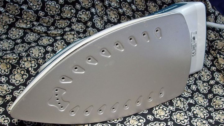 Ein B&uuml;geleisen liegt auf einem gemusterten Stoff und ist bereit, um gereinigt zu werden, was die Pflege des Haushalts unterst&uuml;tzt.