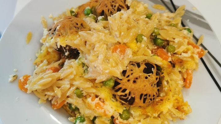 Wikinger-Auflauf serviert auf dem Teller, bestehend aus Kritharaki, Erbsen, Karotten, Hackb&auml;llchen und K&auml;se.