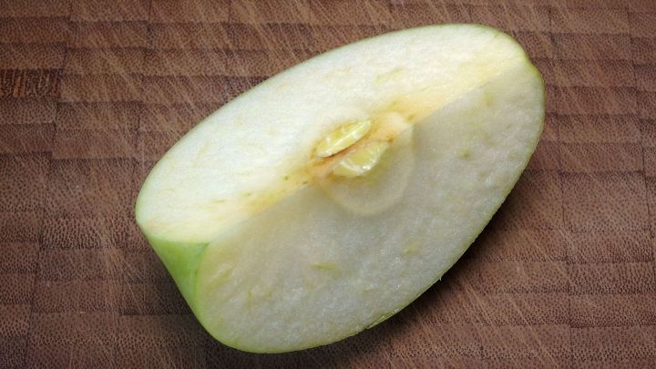 Ein halbierter Apfel liegt auf einem Holzbrett, bereit zum praktischen Sch&auml;len und Verzehr.